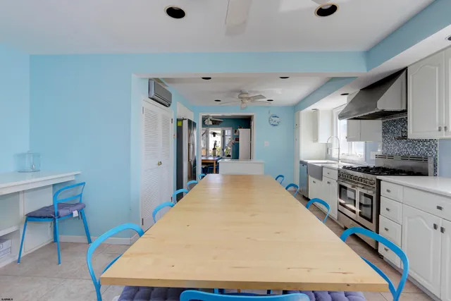 a large kitchen with kitchen island a stove a sink dishwasher and a dining table with wooden floor