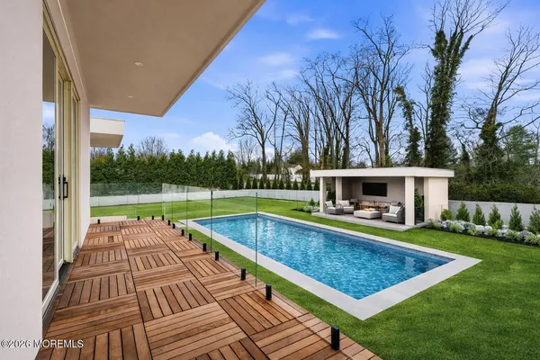 a view of swimming pool with lawn chairs and large trees
