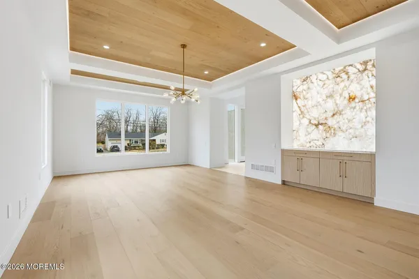 a view of an empty room with a window and chandelier fan