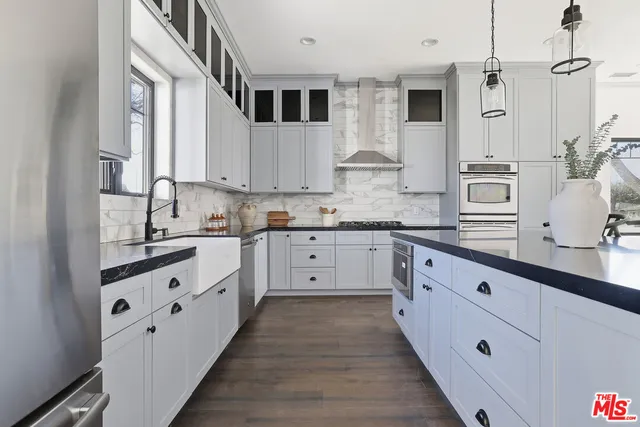 a kitchen with stainless steel appliances granite countertop a stove a sink and white cabinets