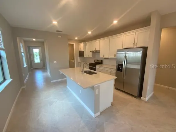 a kitchen with stainless steel appliances granite countertop a refrigerator a sink a stove and a refrigerator with wooden floor