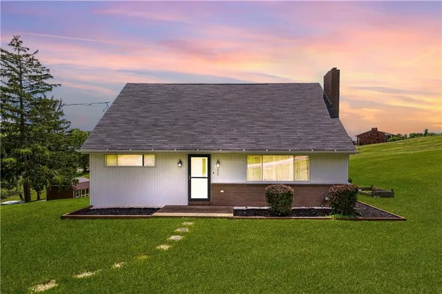 a front view of house with yard and trees in the background