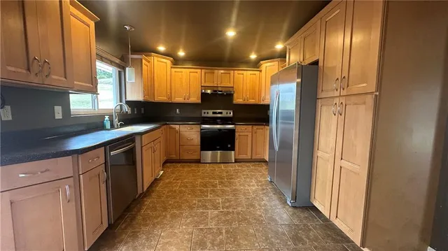 a large kitchen with stainless steel appliances granite countertop a stove a sink and a refrigerator