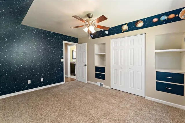 an empty room with closet and fan