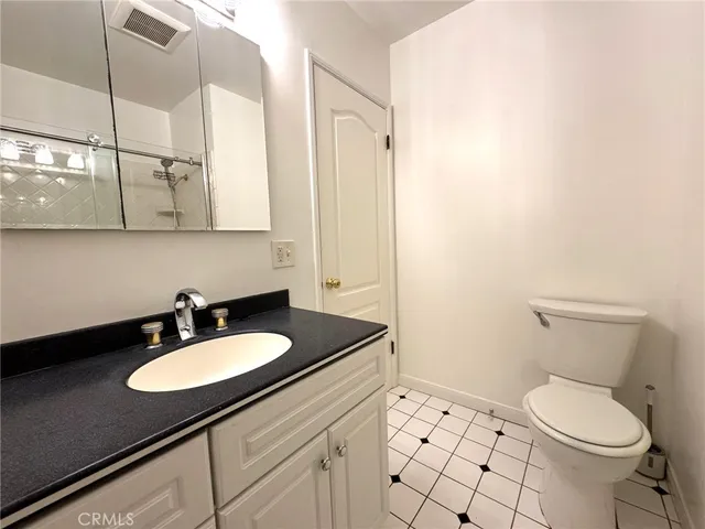 a bathroom with a granite countertop sink mirror vanity and toilet