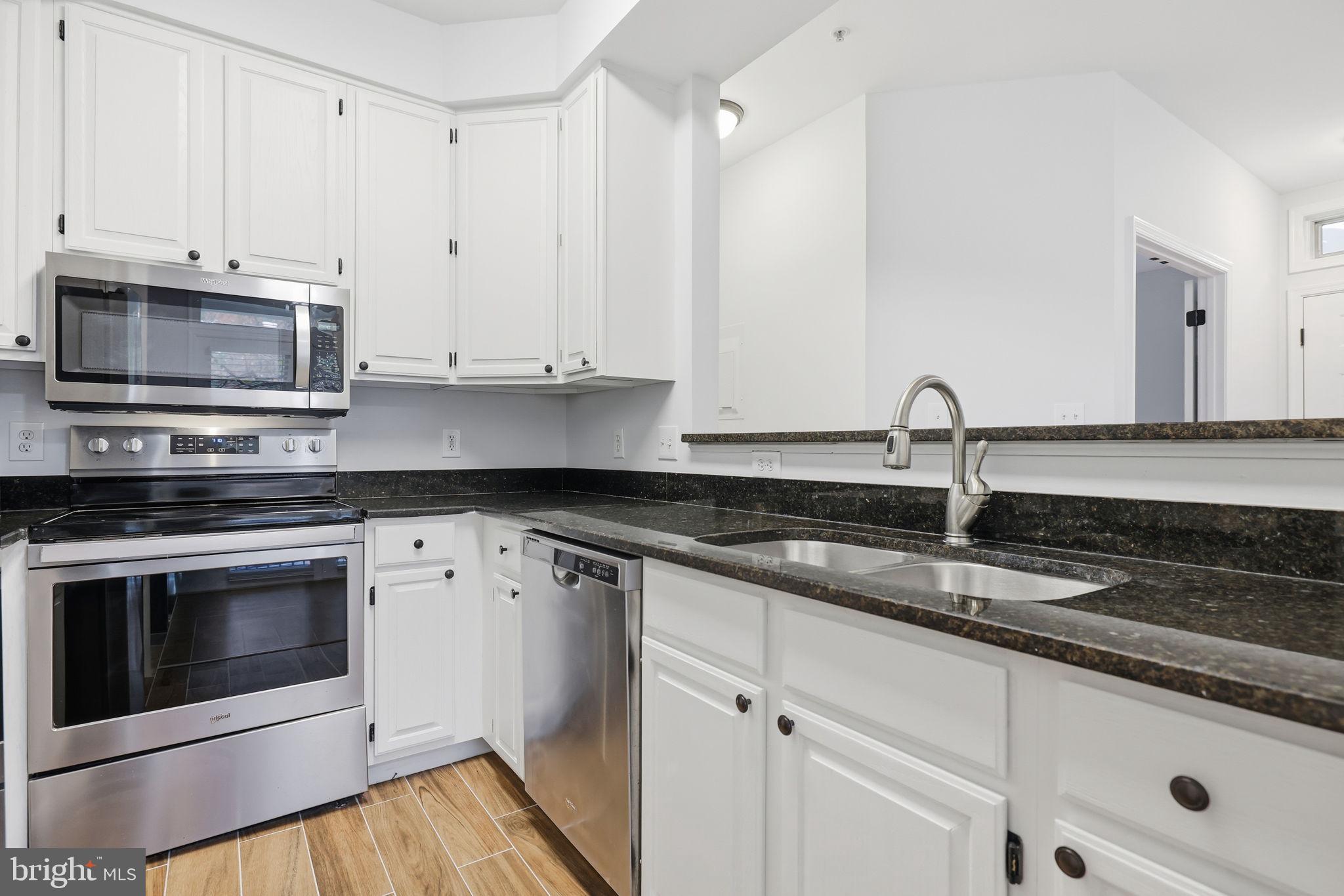 1340 Garden Wall Circle, Unit 502 Reston, VA 20194 - Photo 15 of 32 a kitchen with granite countertop white cabinets white stainless steel appliances and a sink