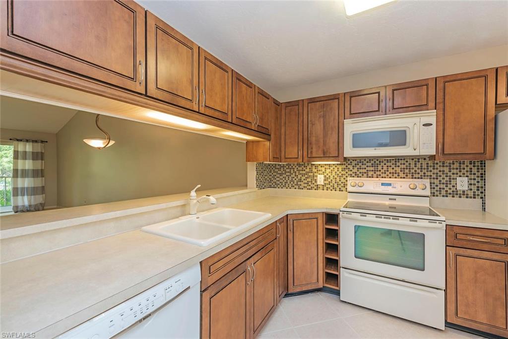 3451 County Barn Road, Unit G204 Naples, FL 34112 - Photo 4 of 12 a kitchen with a sink stove and cabinets