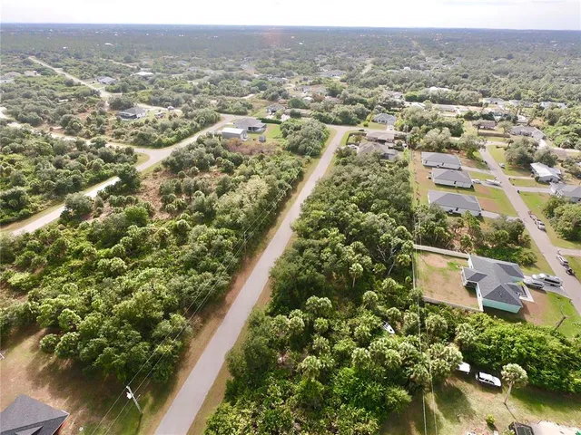 an aerial view of residential houses with outdoor space and trees