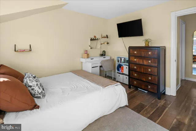 a bedroom with a bed and a flat tv screen on dresser