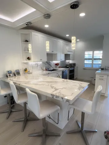 a kitchen with stainless steel appliances kitchen island granite countertop a table chairs sink and cabinets
