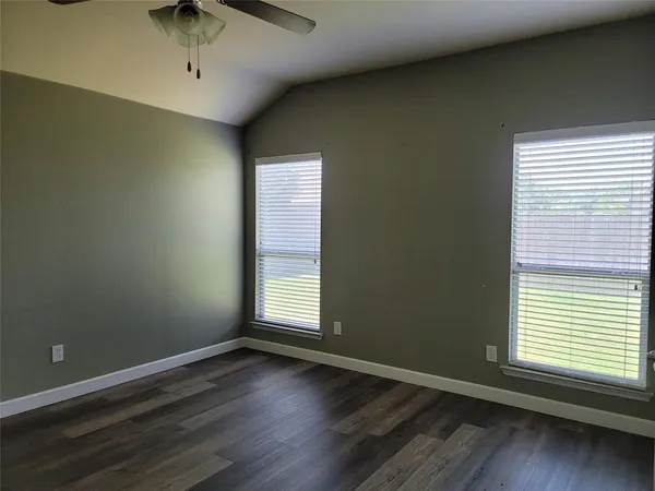 an empty room with wooden floor and windows