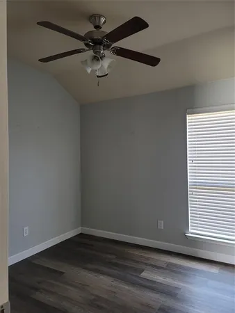 an empty room with wooden floor chandelier fan and windows