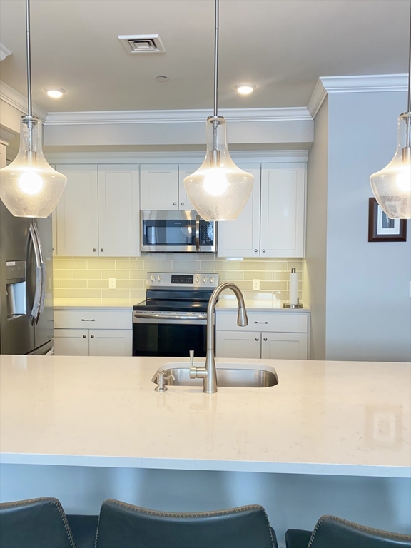 635 Old Post Road, Unit 2203 Sharon, MA 02067 - Photo 10 of 40 a kitchen with kitchen island a sink and a stove