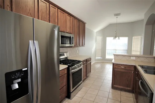 a kitchen with granite countertop a refrigerator stove and sink