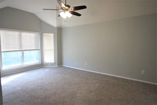 an empty room with windows and fan