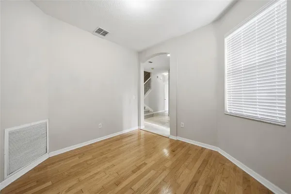 a view of an empty room with wooden floor and a window
