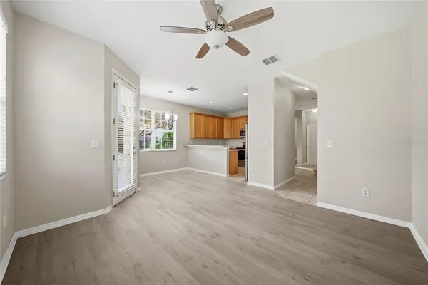 an empty room with wooden floor ceiling fan and windows
