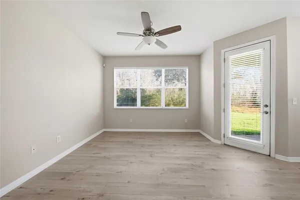 an empty room with windows and ceiling fan