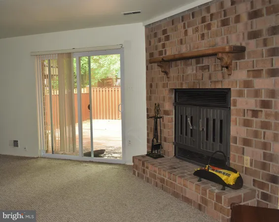 a view of an empty room with a fireplace and windows