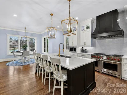 a kitchen with stainless steel appliances granite countertop a stove a sink a microwave a dining table and chairs