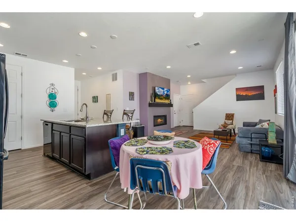a kitchen with stainless steel appliances kitchen island granite countertop a table chairs and a refrigerator