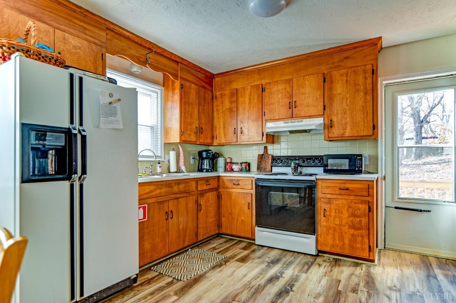 207 Matohe Road Monroe, VA 24574 - Photo 6 of 34 a kitchen with stainless steel appliances granite countertop a refrigerator a sink dishwasher a stove and white countertops with wooden floor