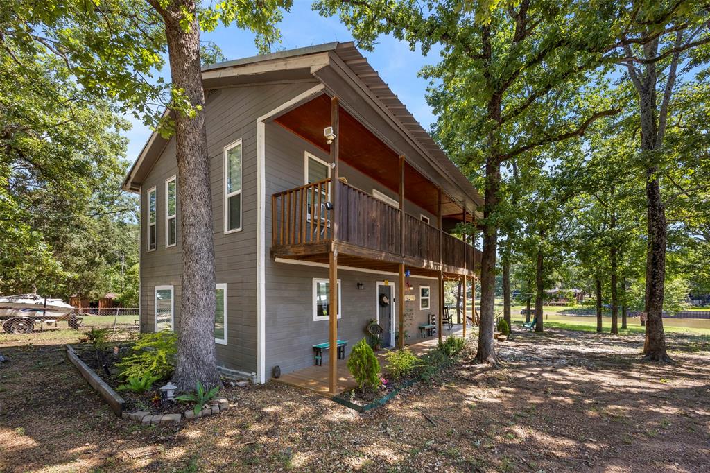 7110 Apache Circle Mabank, TX 75156 - Photo 7 of 39 Two-story residence featuring gray siding with white trim, a metal roof, and a full-length balcony