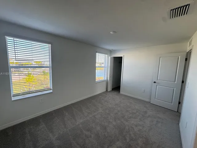 a view of an empty room with window and closet area