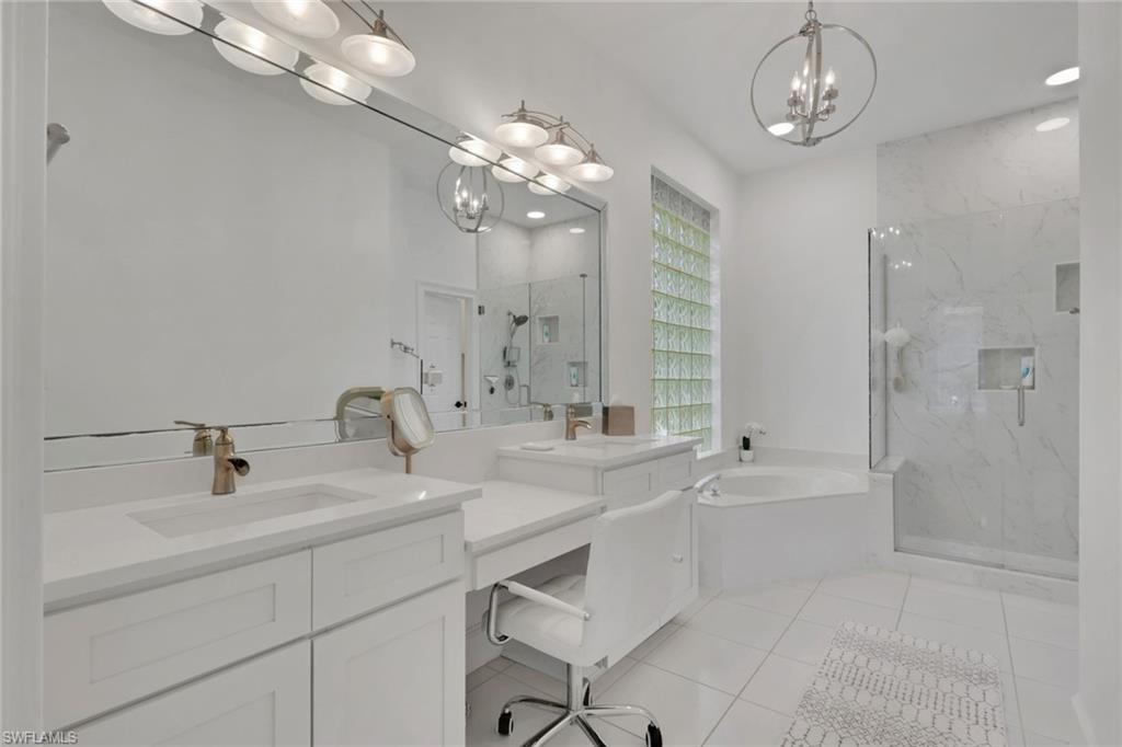 136 April Sound Drive Naples, FL 34119 - Photo 11 of 24 a bathroom with a sink a large mirror and a bathtub