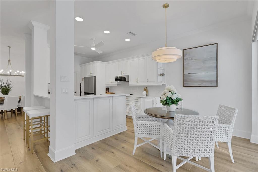 136 April Sound Drive Naples, FL 34119 - Photo 6 of 24 a kitchen with granite countertop white cabinets and chairs