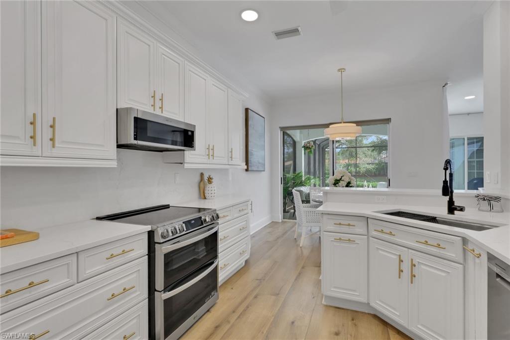 136 April Sound Drive Naples, FL 34119 - Photo 8 of 24 a kitchen with white cabinets stainless steel appliances and sink