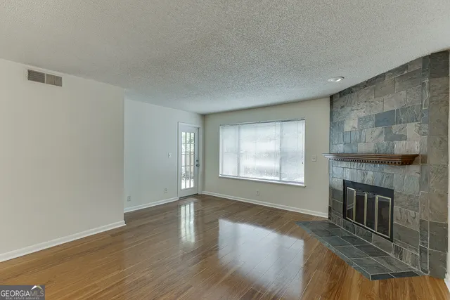 an empty room with wooden floor fireplace and windows