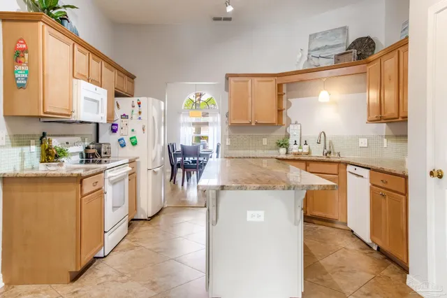 a large kitchen with stainless steel appliances granite countertop lots of counter top space and wooden floor
