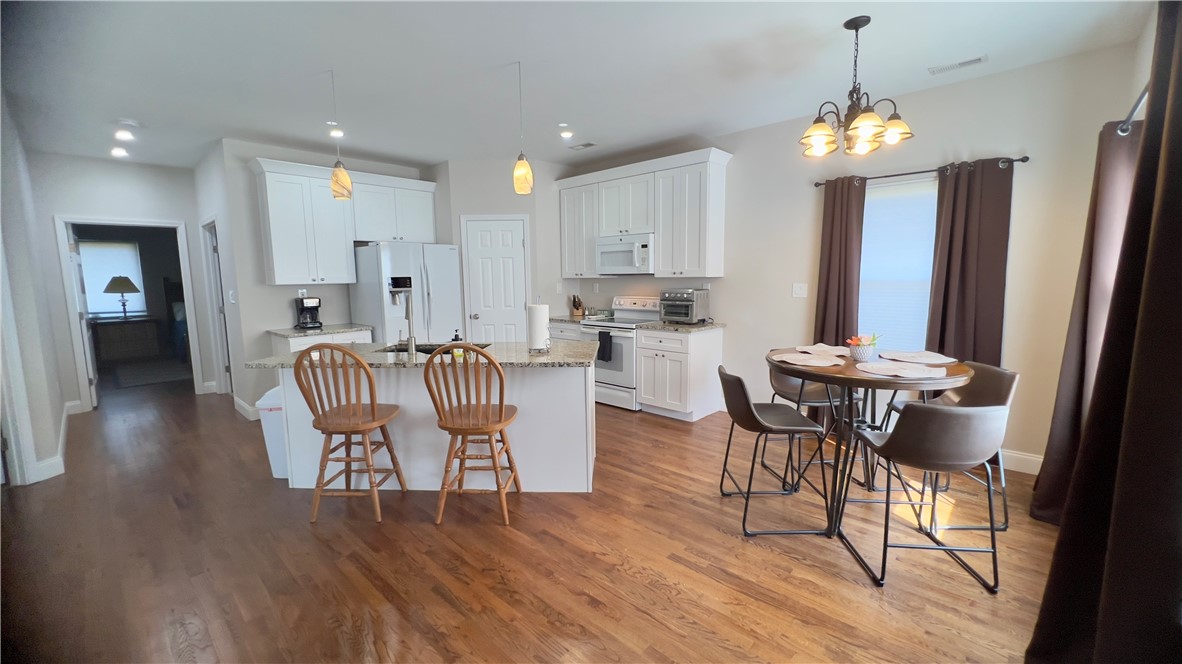 160 Hudgins Lake Road Townville, SC 29689 - Photo 8 of 41 A warm kitchen and dining space with rich hardwood floors and functional island seating.