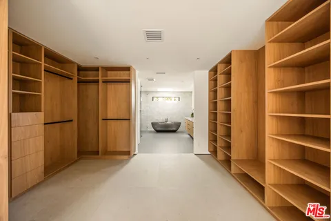 a view of walk in closet with clothes and shoes