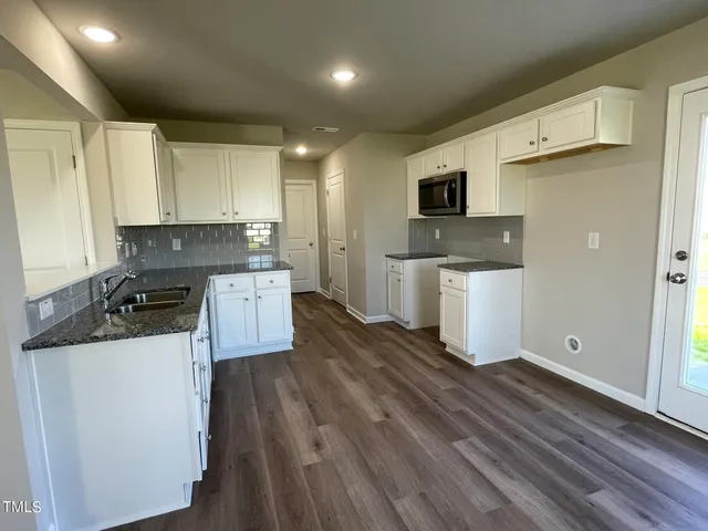 a kitchen with a sink and wooden floor