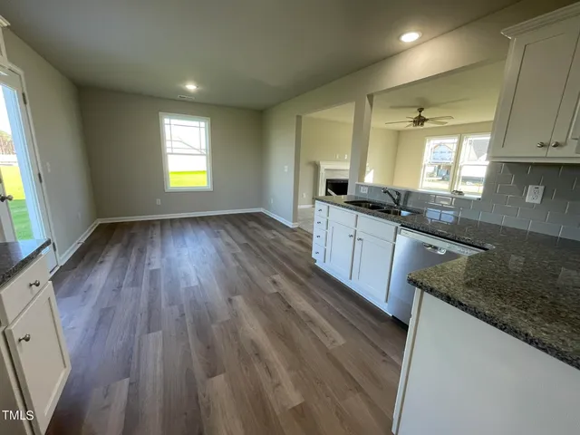 a large kitchen with granite countertop a sink window and wooden floor