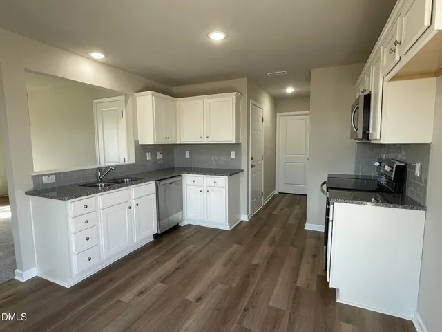 a kitchen with granite countertop a sink cabinets and wooden floor