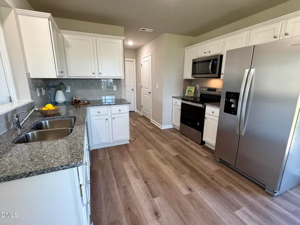 a kitchen with stainless steel appliances granite countertop a refrigerator a stove microwave and sink