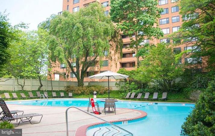 110 Cross Keys Road, Unit R110F Baltimore, MD 21210 - Photo 28 of 30 a view of a swimming pool with a table and chairs under an umbrella