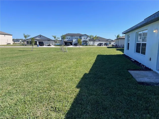 a view of a house with a yard and a large tree