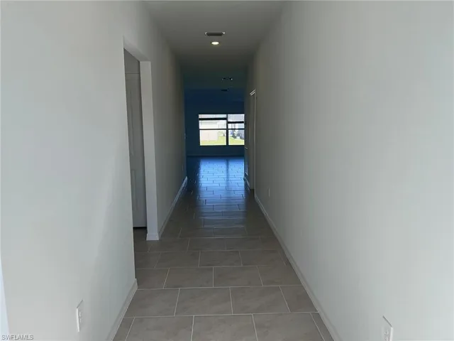 a hallway with wooden floor and a window