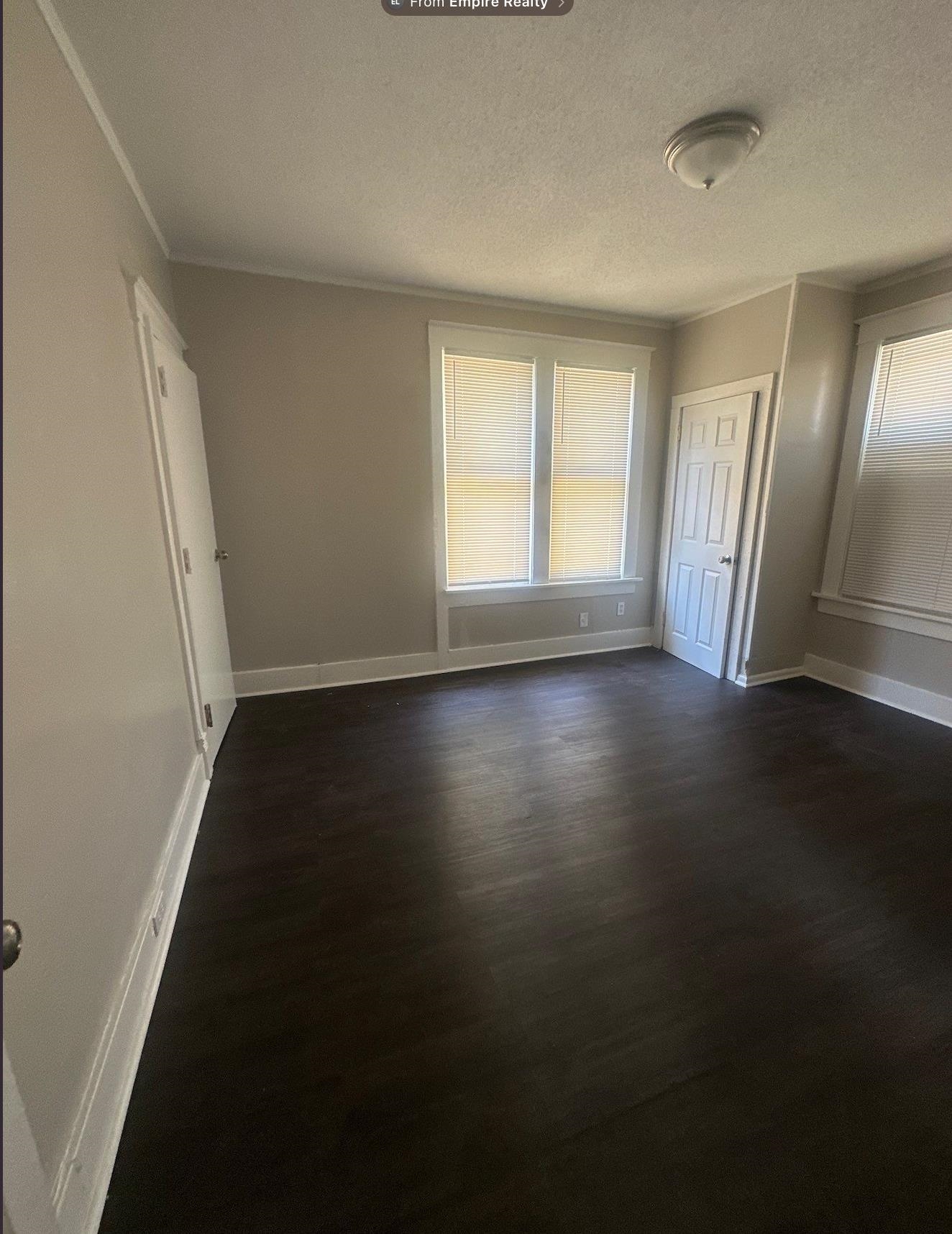 1165 Rayner Street Memphis, TN 38106 - Photo 5 of 16 Room featuring dark wood-finish flooring, light-colored walls, white trim, and multiple windows with blinds