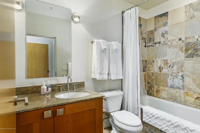 a bathroom with a granite countertop sink toilet a mirror a bathtub and shower