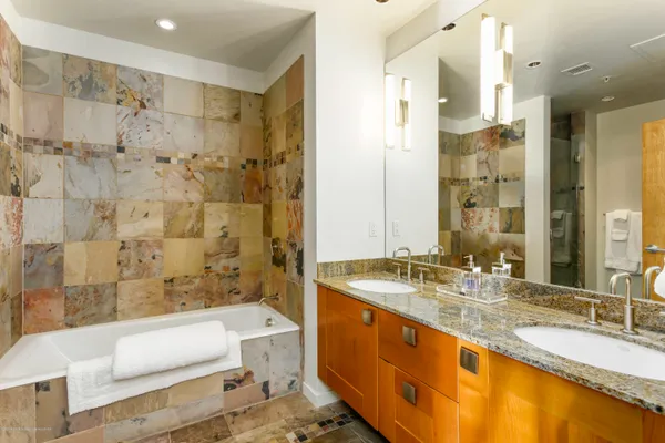 a bathroom with a granite countertop tub sink and double vanity