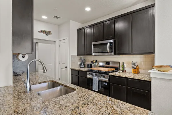 a kitchen with granite countertop a sink stainless steel appliances and cabinets
