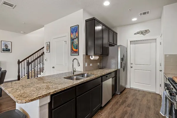 a kitchen with stainless steel appliances granite countertop a sink refrigerator and cabinets
