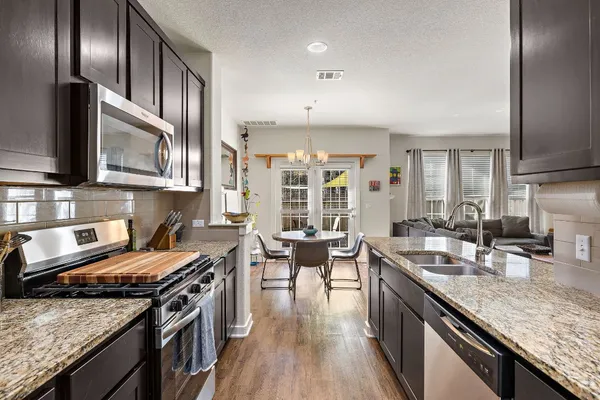 a kitchen with granite countertop lots of counter top space a sink and stainless steel appliances