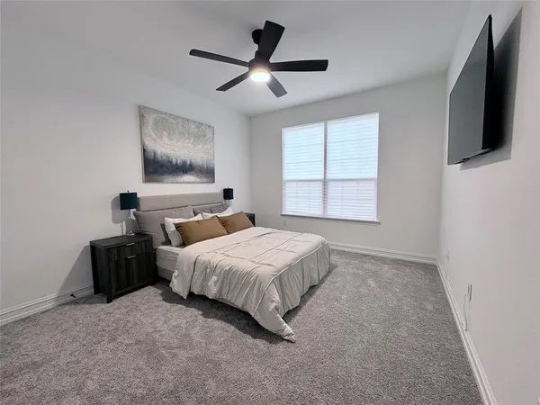 a bedroom with a bed and a flat tv screen on the dresser