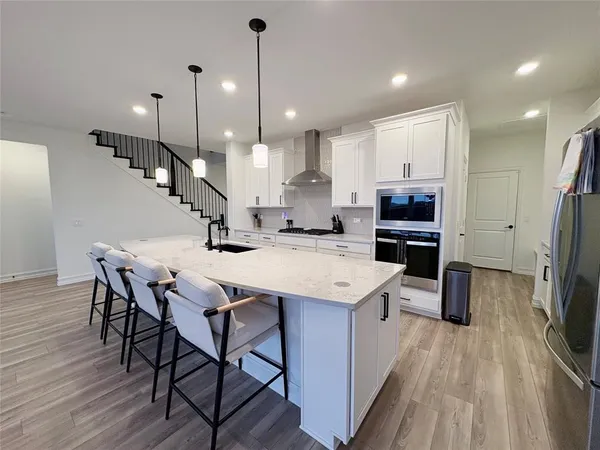 a kitchen with stainless steel appliances kitchen island granite countertop a table chairs refrigerator and microwave